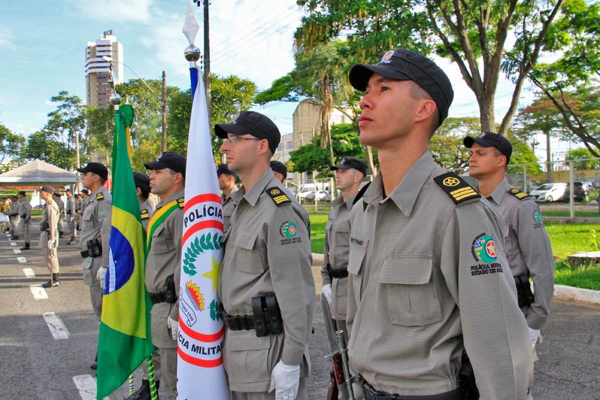 Policiais militares de Goiás em posição de sentido segurando as bandeiras do Brasil e da corporação