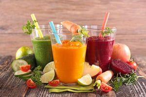 Foto com três copos de suco rodeados por frutas - Metrópoles