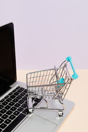 Carrinho de compras em miniatura em cima de teclado de laptop isenção - Metrópoles