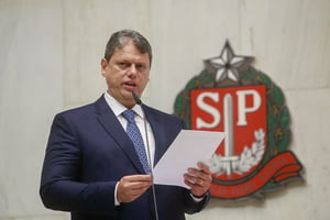 foto colorida do governador de São Paulo, Tarcísio de Freitas, atrás de um brasão do governo paulista - Metrópoles