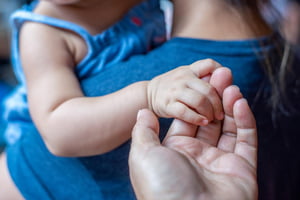 Foto colorida de um bebê segurando uma mão - Metrópoles