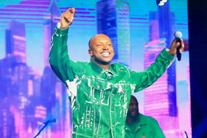 Foto colorida de Thiaguinho cantando no palco vestindo uma roupa verde - Metrópoles