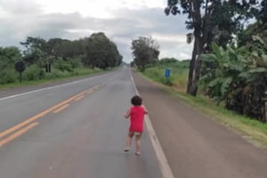 Imagem colorida mostra o momento em que criança é resgatada vagando em estrada - Metrópoles