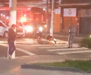 Imagem de homem levando tiro de taser, deitado no meio de avenida; PMs o cercam - Metrópoles