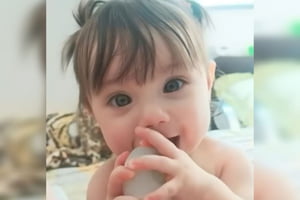 Imagem de bebê com olhos azuis e objeto na boca - Metrópoles
