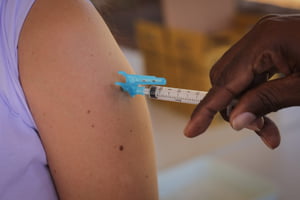 Foto colorida com zoom de pessoa recebendo vacina - Metrópoles