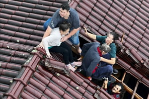 foto colorida de vítimas ilhadas em telhado no RS no momento em que são resgatadas por PMs de SP - Metrópoles