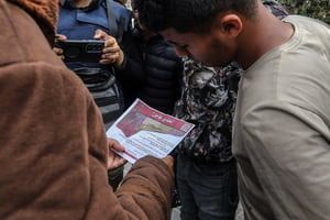 Palestinos seguram um panfleto lançado pela aeronave militar do exército de Israel ordenando que evacuem evacuem Rafah e se movam em direção ao oeste da cidade