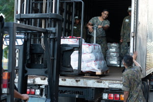 Fotografia colorida mostrando militar descarregando alimentos de caminhão-Metrópoles