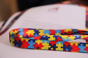 Foto colorida de cordão colorido com quebra-cabeça, simbolizando autismo