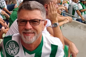 Homem branco, de cavanhaque a cabelos grisalhos, usando óculos e camiseta do Palmeiras, em arquibancada de estádio - Metrópoles