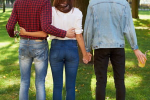 Foto colorida de três pessoas de costas dandos as mãos - Metrópoles