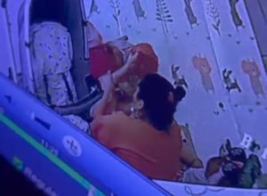 Foto colorida retirada de câmera de segurança que mostra babá praticando maus-tratos contra bebê e criança - Metrópoles