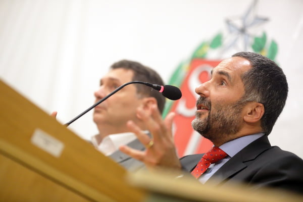 Imagem colorida mostra Mario Sarrubbo, homem branco, grisalho, de barba aparada, falando ao microfone - Metrópoles