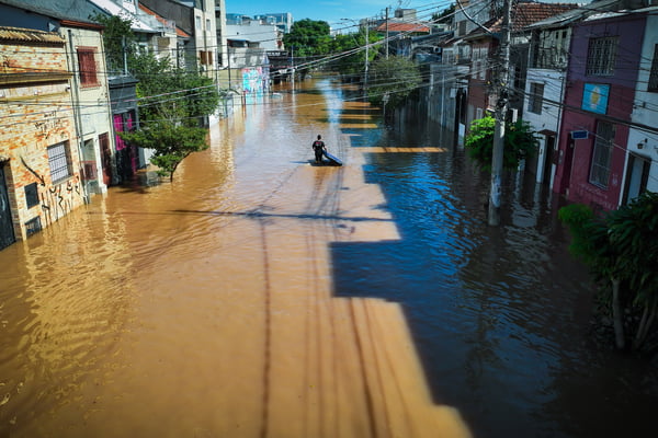 Morador caminha com colchão em rua após enchente do rio Guaíba - Metrópoles