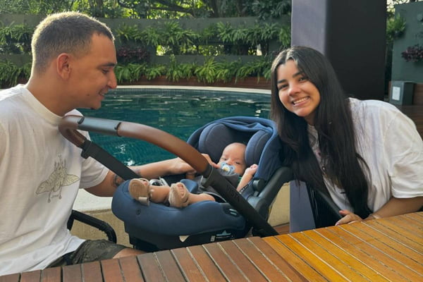 foto colorida de joão gomes ao lado de mulher e bebe em carrinho - metrópoles