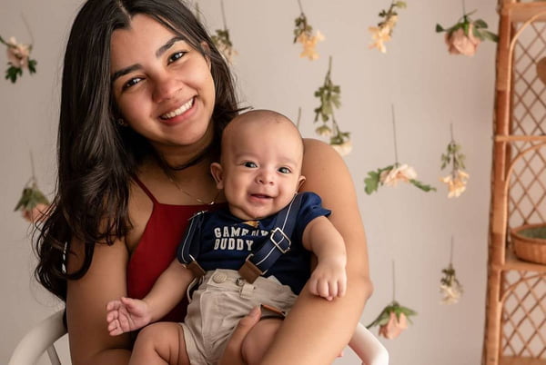 foto colorida de mulher com bebe no colo sorrindo - metrópoles