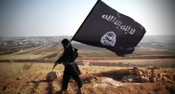 Imagem colorida mostra um jihadista segurando uma bandeira do Estado Islâmico - Metrópoles