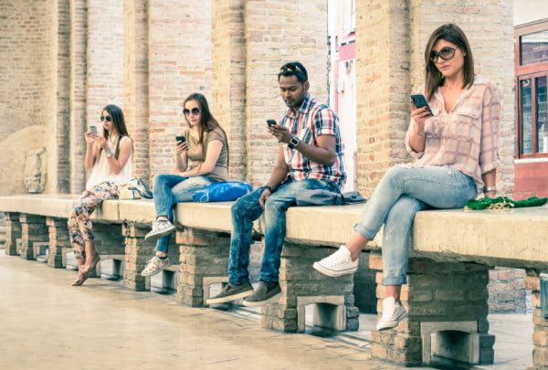 Group of young multiracial friends using smartphone with mutual
