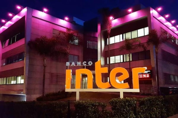Imagem da fachada do Banco Inter, à noite, com o prédio iluminado