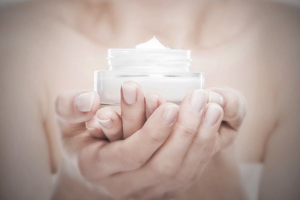 Woman’s hands holding a face creme jar.