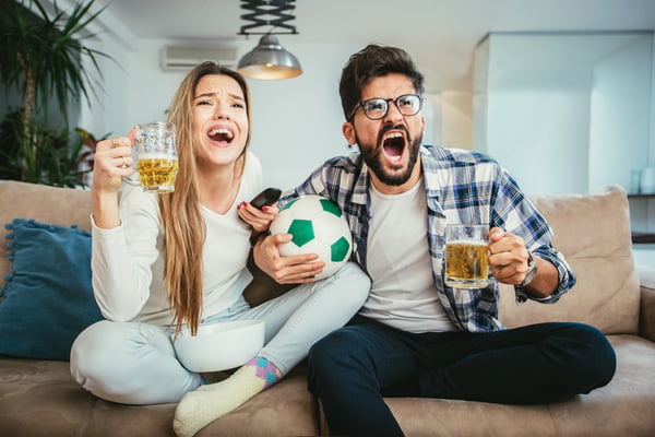 Couple watching tv in living room while eating popcorn and drinking beer