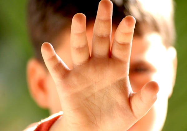 Criança com mão tapando o rosto - Metrópoles