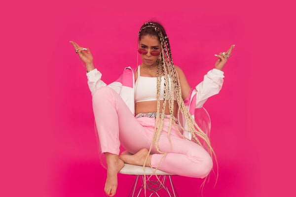 Flora Matos. Ela está de top branco e calça rosa claro. O fundo é rosa - Metrópoles