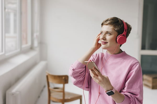 Smiling woman with cell phone and headphones listening to music