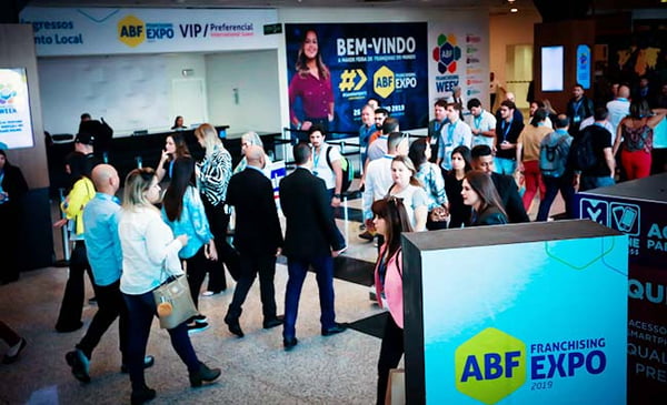 Imagem de evento da Associação Brasileira de Franchising (ABF), com muitas pessoas caminhando e diversos painéis da entidade - Metrópoles