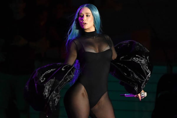 Imagem colorida mostra cantora iggy azalea. ela tem cabelo azul, veste roupa preta e segura um microfone- metrópoles