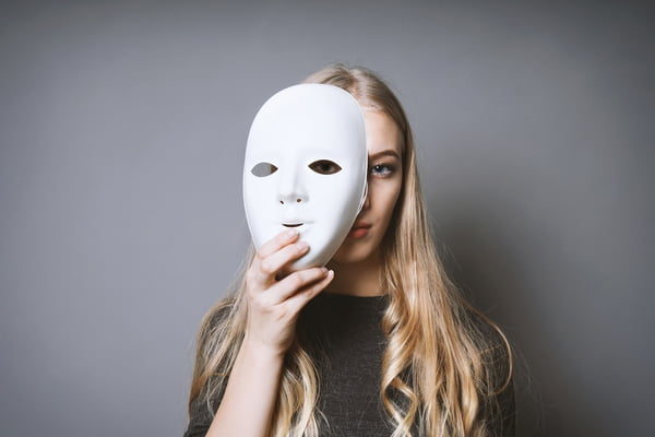 Portrait Of Girl Holding Mask Against Gray Background