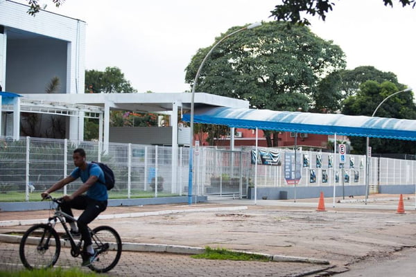 jovem anda de bicicleta em frente a colégio fechado na Asa Sul