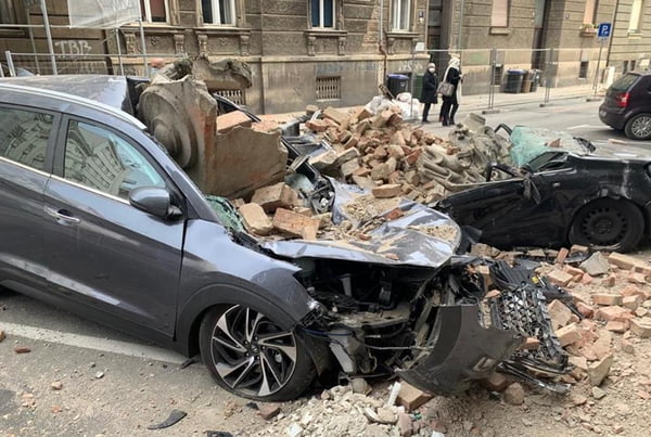 Carros destruidos por escombros e partes de edifício que desabaram em meio ao terremoto na Croácia