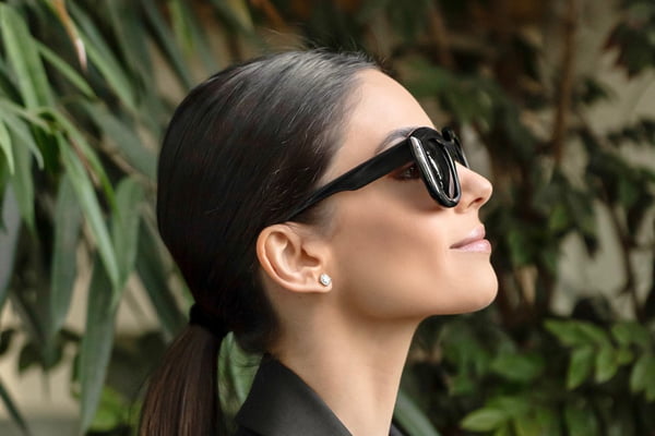 Caroline Celico, de perfil, usando óculos de sol pretos