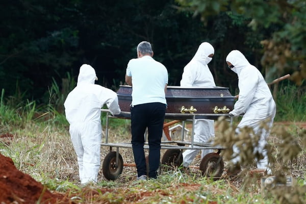 coveiros vestindo roupas especiais enterram vítima da covid-19 em cemitério de goiânia, goiás