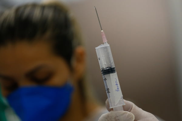 Enfermeira segurando seringa com fentanil, relaxante muscular que auxilia na intubação de pacientes