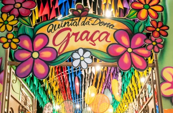 Placa escrito Quintal da Dona Graça com bandeirinhas juninas acima
