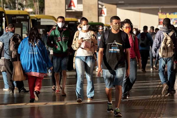 Pessoas andam na rua de máscara