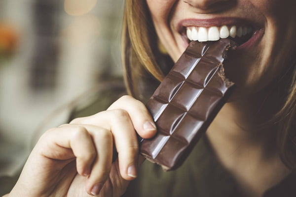 Mulher comendo barra de chocolate