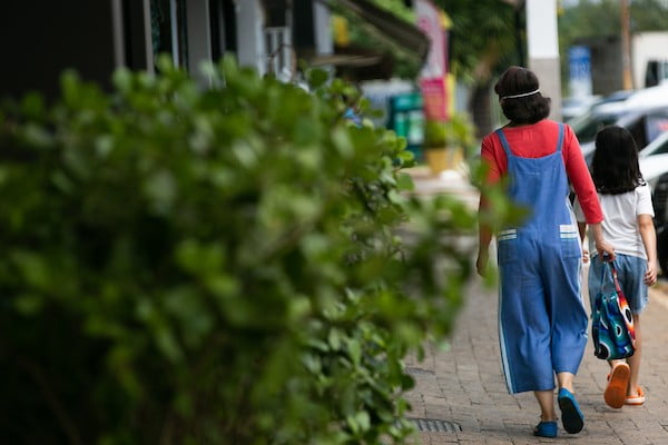 Na fotografia colorida, a mulher aparece de costas andando na rua