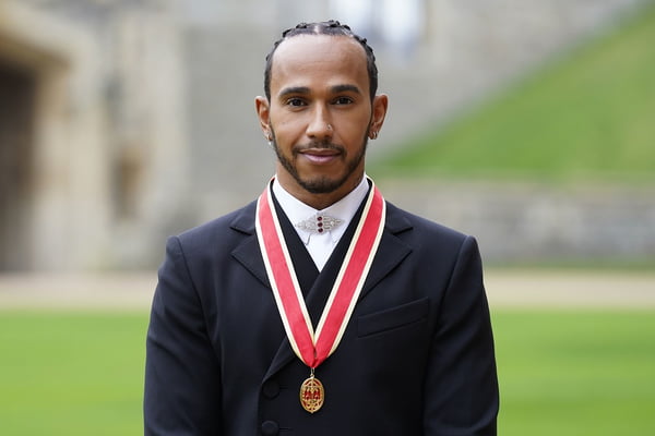 Homem de terno com faixa vermelha no pescoço e medalha