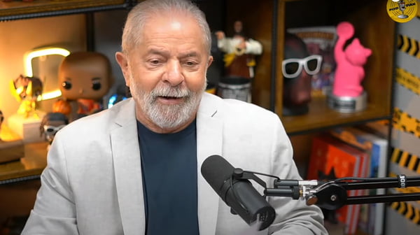 Ex-presidente no podcast PodPah, no YouTube. Ele está na frente de um cenário colorido, no estúdio do programa, e fala num microfone especial - Metrópoles