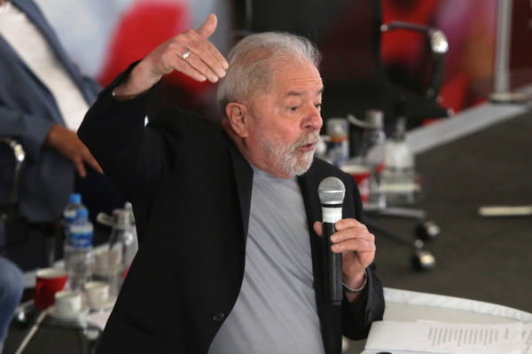 Lula no sindicato dos metalúrgicos no ABC. Ele está de pé, com um microfone na mão, gesticulando e discursando. Usa terno e camiseta por baixo - Metrópoles
