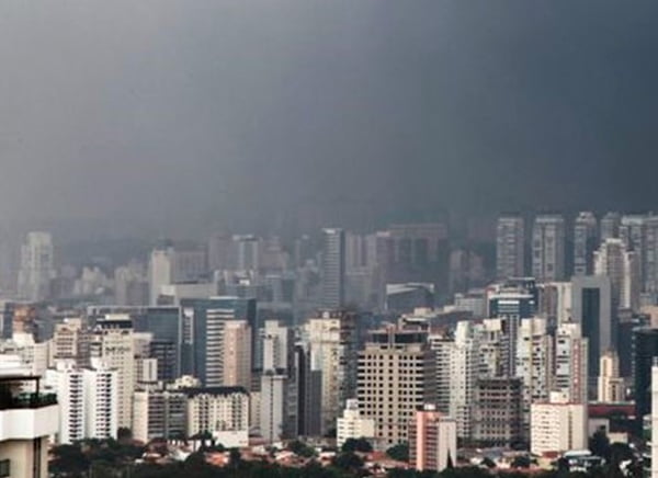 Na imagem colorida, prédios estão posicionados no centro. o céu está com neblina em dia de fortes temporais em São Paulo
