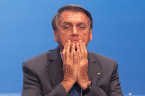 Bolsonaro com as mãos no rosto em evento de acesso ao crédito promovido no Planalto, sob fundo azul - Metrópoles