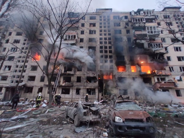 Prédio em chamas e cenário em frente destruido por bombardeios russos
