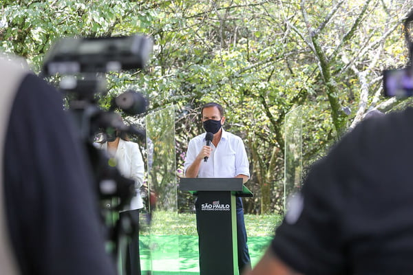 O governador de São Paulo, João Doria, fala ao microfone ao conceder uma entrevista coletiva na área externa do Palácio dos Bandeirantes