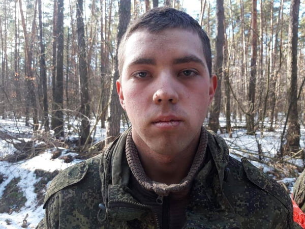 Rafik Rahmankulov, de 19 anos, um dos soldados russos capturados na invasão russa na Ucrânia. Ele tem olhos azuis, pele clara e cabelo curto, usando trajes militares numa floresta - Metrópoles
