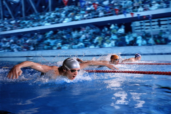 Disputa de natação com 3 nadadores aparecendo no ângulo captado